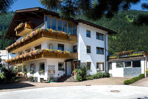 Gästehaus Gstrein im Sommer mit blühenden Balkonen vor Tiroler Bergkulisse